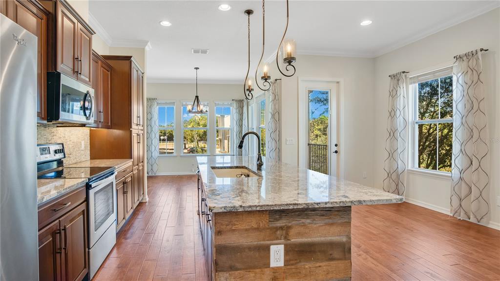 A kitchen features dark wood cabinets, granite countertops, a rustic wood island, and hardwood floors — 921 TARAMUNDI DRIVE, OVIEDO, FL