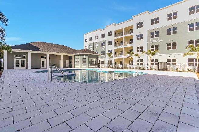 A swimming pool sits on a paved patio beside a multi-story apartment building — 1220 SOUTHSTATION PLACE UNIT 404, ORLANDO, FL