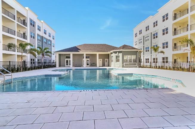 A swimming pool sits in a courtyard between two multi-story apartment buildings — 1220 SOUTHSTATION PLACE UNIT 404, ORLANDO, FL