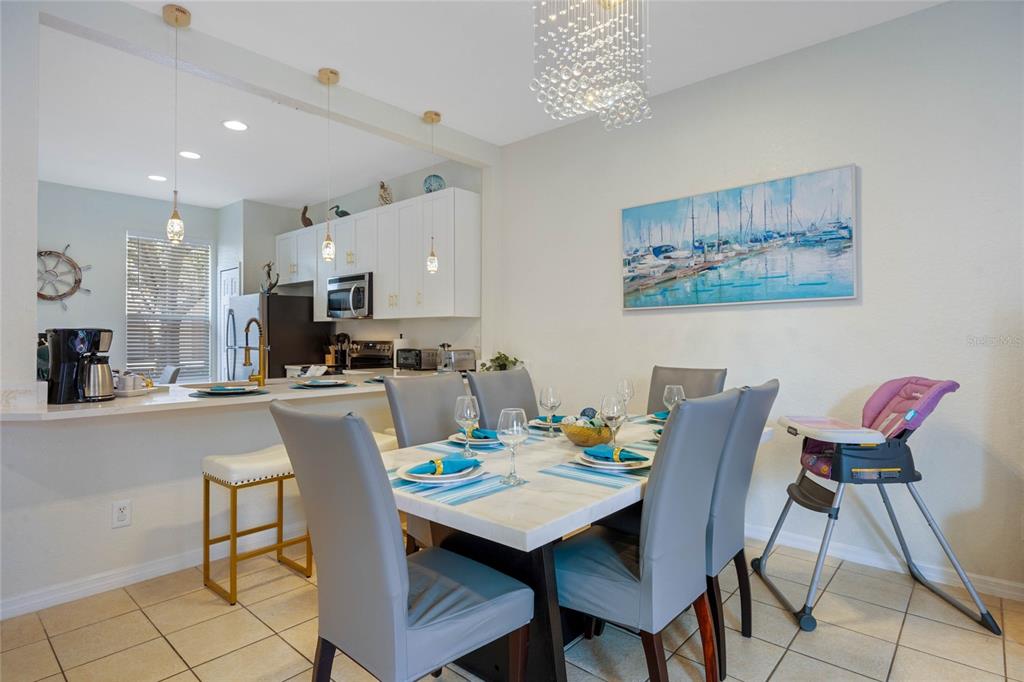 A dining area with a marble-topped table, grey chairs, and an adjacent kitchen breakfast bar — 2705 IMPALA LANE, KISSIMMEE, FL