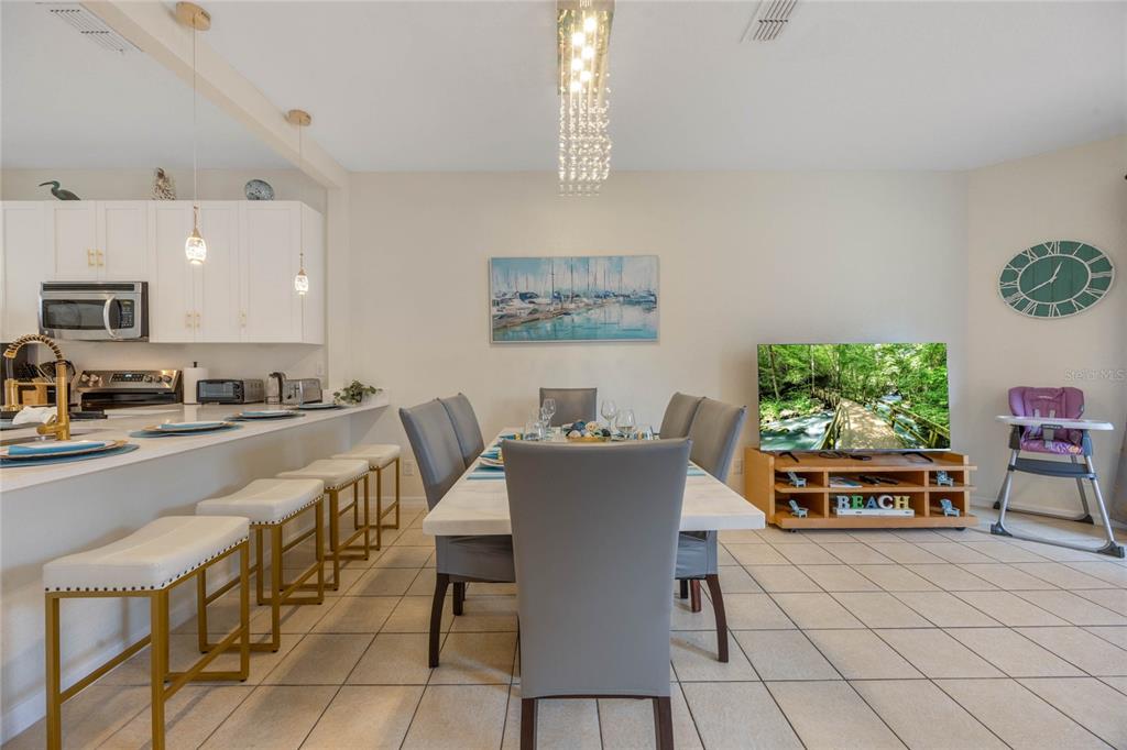 A dining area with a table and chairs sits adjacent to a kitchen breakfast bar — 2705 IMPALA LANE, KISSIMMEE, FL
