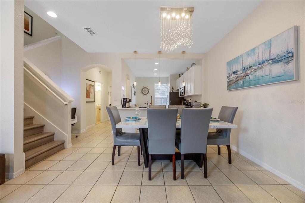 A dining area features a table with four grey chairs, tile flooring, and a chandelier — 2705 IMPALA LANE, KISSIMMEE, FL