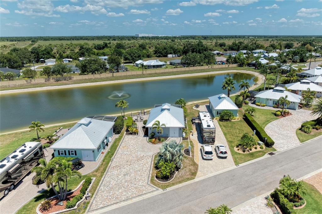 An aerial view shows three small houses with metal roofs and RVs near a pond — 8239 SW SAND CRANE CIRCLE LOT 11, ARCADIA, FL