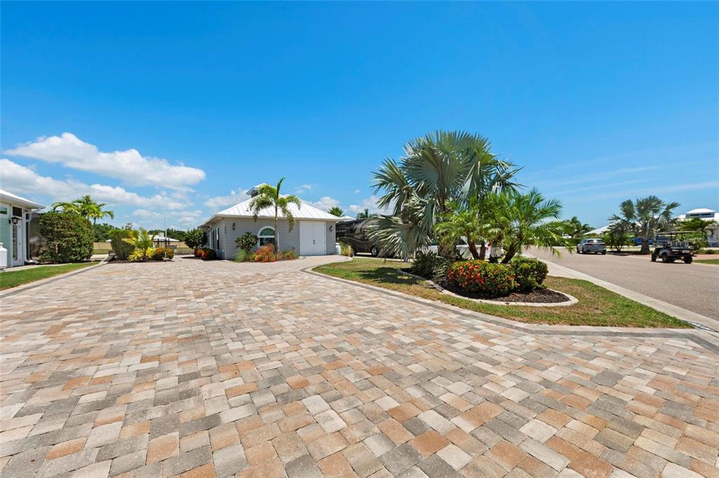 A paved driveway leads to a light gray detached garage surrounded by tropical landscaping — 8239 SW SAND CRANE CIRCLE LOT 11, ARCADIA, FL