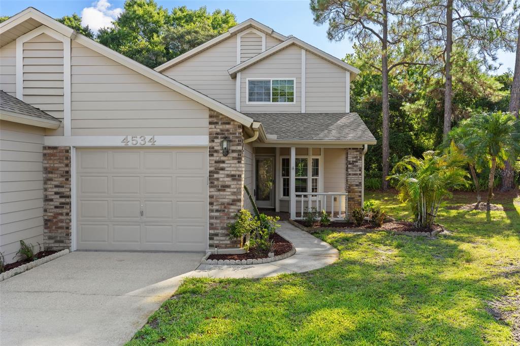 A two-story house with beige siding, a brick-accented garage, and a small front porch — 4534 SLIPPERY ROCK ROAD, NEW PORT RICHEY, FL