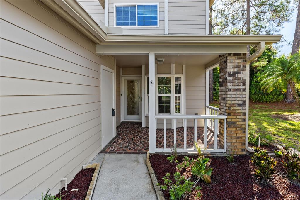 A covered porch with a tiled floor leads to a front door and a window — 4534 SLIPPERY ROCK ROAD, NEW PORT RICHEY, FL