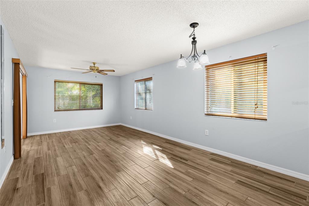 An empty room with light blue walls, wood-look tile flooring, and a ceiling fan — 4534 SLIPPERY ROCK ROAD, NEW PORT RICHEY, FL