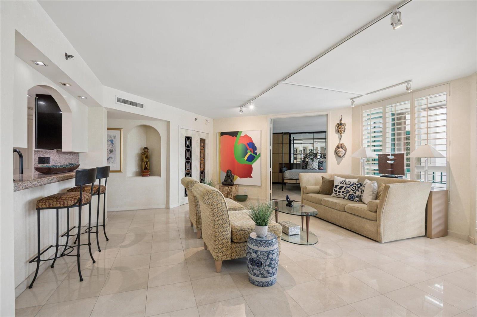 A living room with tile floors, a breakfast bar, and a view into a bedroom — 120 SE 5th Avenue # 329, Boca Raton FL 33432, BOCA RATON, FL