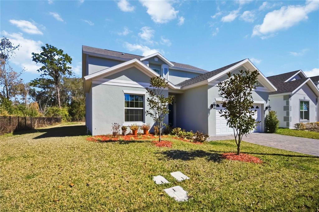 A single-story house with a light-colored stucco exterior, a two-car garage, and a front lawn — 827 DENNIS AVENUE, ORLANDO, FL
