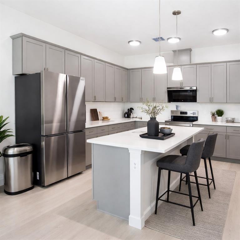 A modern kitchen features gray cabinets, stainless steel appliances, and a white-topped center island — 827 DENNIS AVENUE, ORLANDO, FL