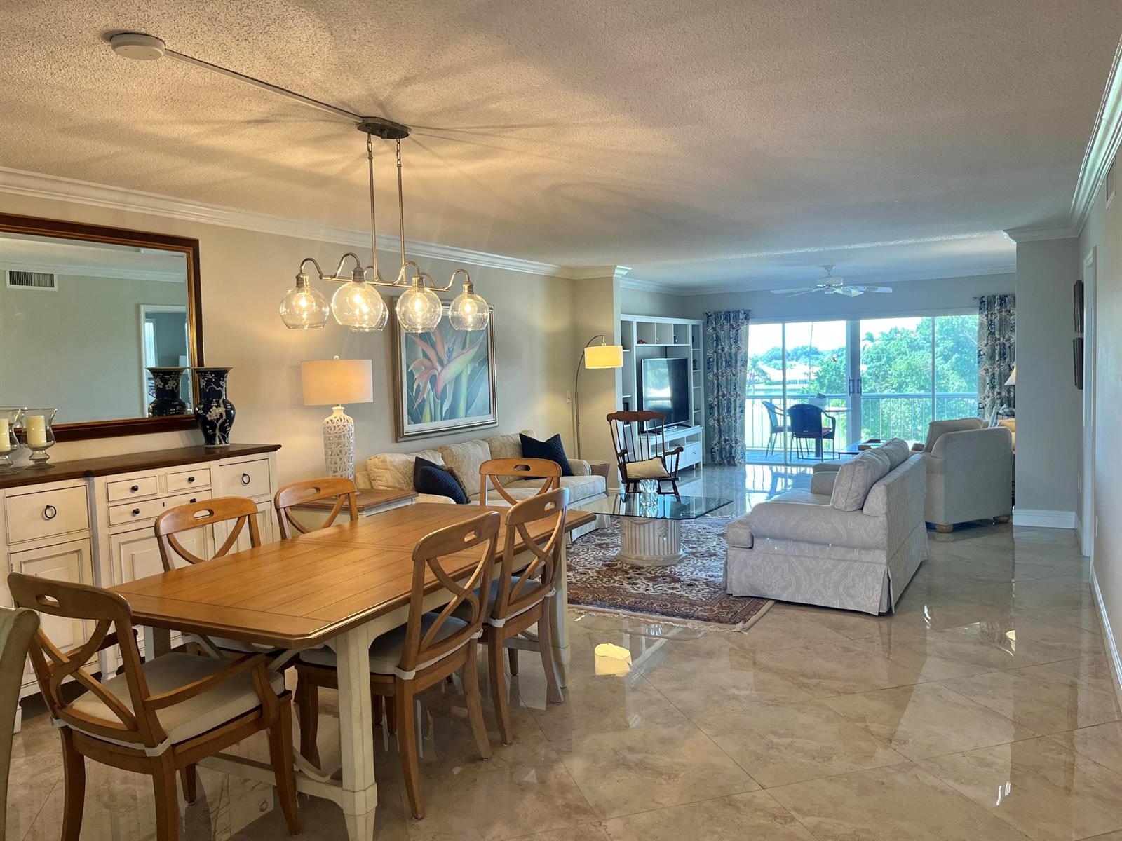 A dining area and living room with tile floors, a chandelier, and a balcony view — 145 Atlantis Boulevard, Atlantis FL 33462, ATLANTIS, FL