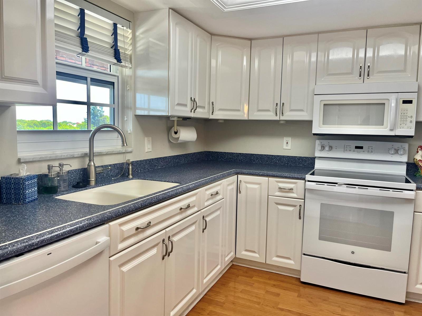 A kitchen features white cabinetry, blue speckled countertops, a white sink, and white appliances — 145 Atlantis Boulevard, Atlantis FL 33462, ATLANTIS, FL