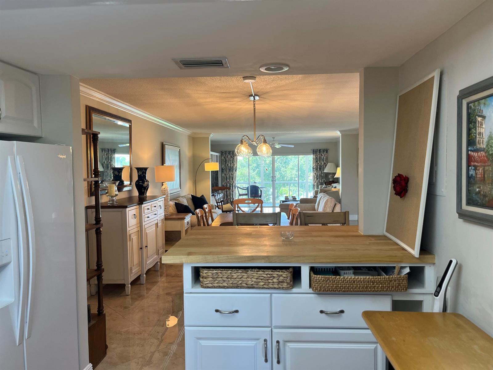 A kitchen island with a wood countertop overlooks an open-concept dining and living area — 145 Atlantis Boulevard, Atlantis FL 33462, ATLANTIS, FL