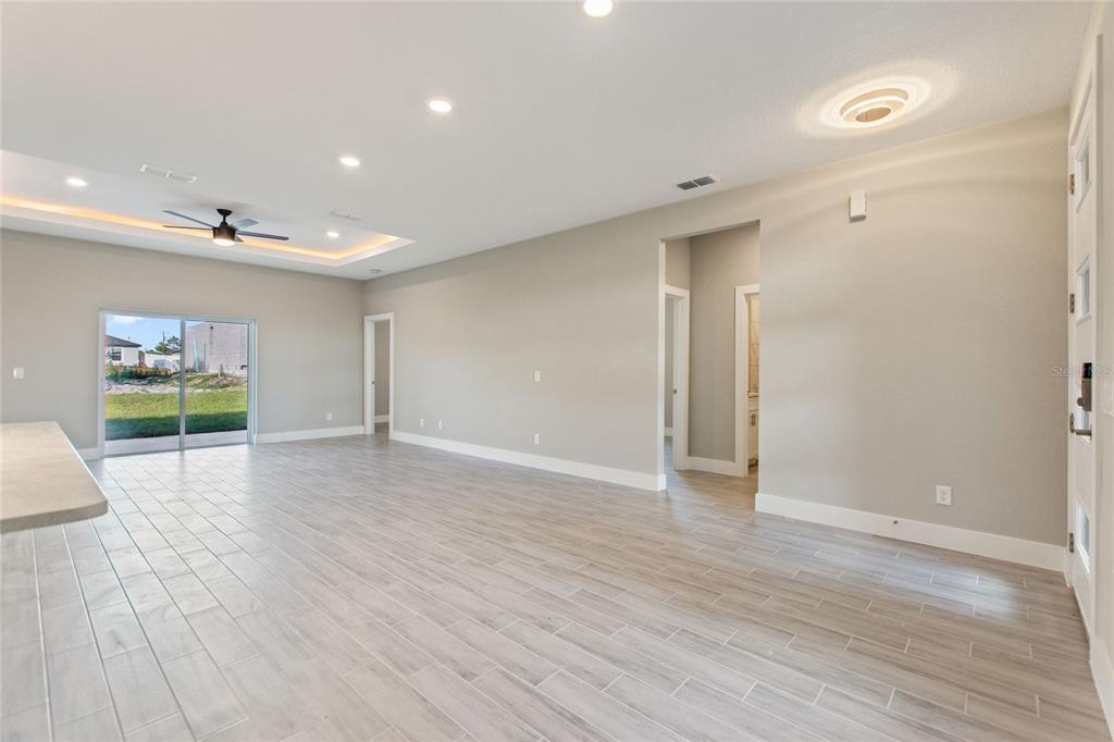 A spacious room with light-colored tile flooring, recessed lighting, a ceiling fan, and sliding doors — 119 TULIP LANE, KISSIMMEE, FL