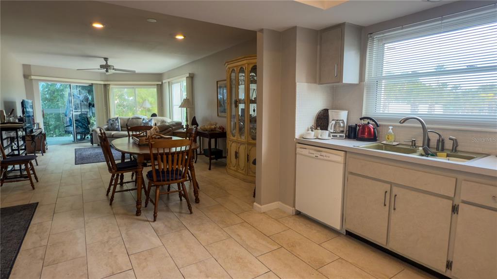 A kitchen with white cabinets and tile flooring opens into a dining and living area — 1900 BENJAMIN FRANKLIN DRIVE UNIT 201BER, SARASOTA, FL