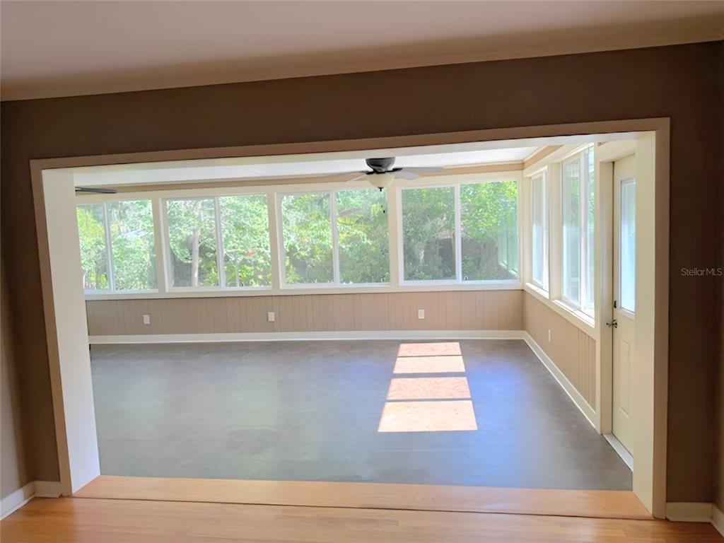 A sunroom with large windows, a ceiling fan, and gray flooring viewed from an adjacent room — 2143 SE 3RD STREET, OCALA, FL