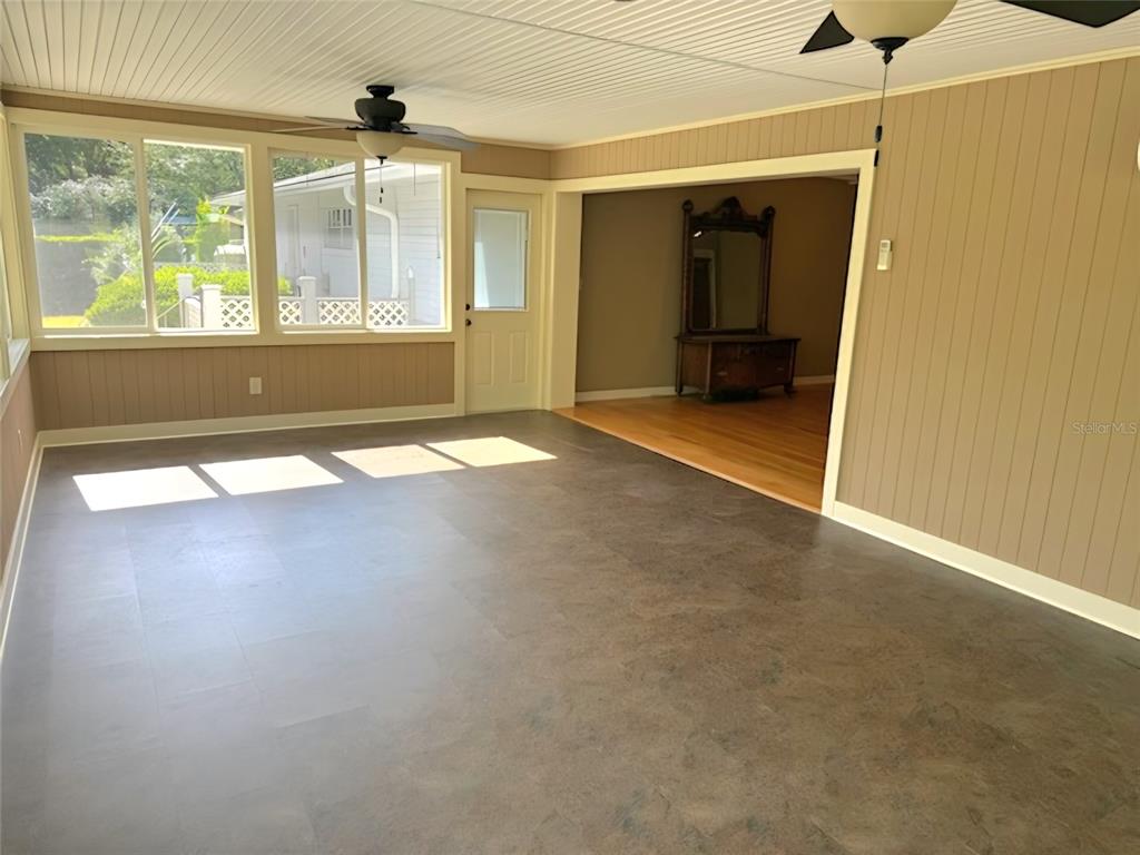 A sunroom with dark tile flooring, wood-paneled walls, and a doorway leading to another room — 2143 SE 3RD STREET, OCALA, FL