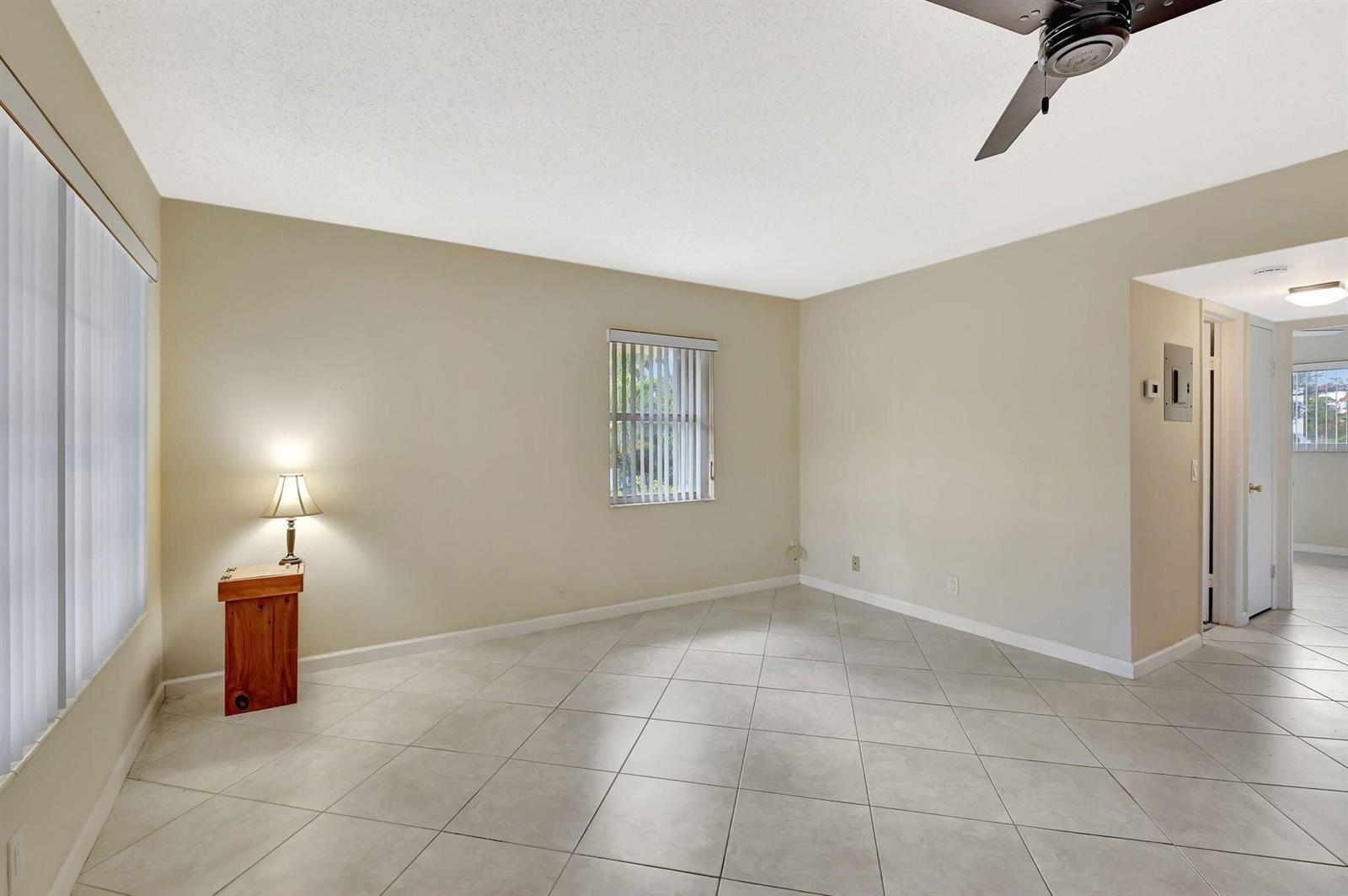 An empty room with beige walls, light-colored tile flooring, a ceiling fan, and a window — 638 Snug Harbor Drive # E11, Boynton Beach FL 33435, BOYNTON BEACH, FL
