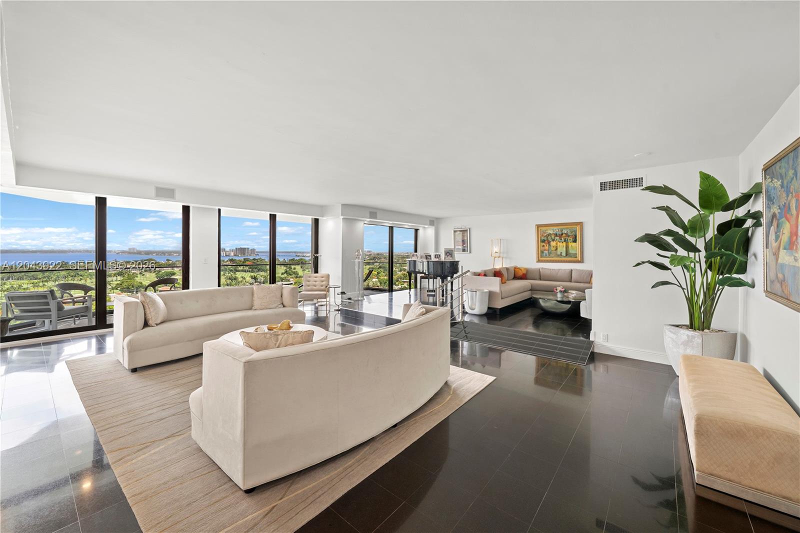 A spacious living room features dark tile floors, two beige sofas, and floor-to-ceiling windows — 5500 Collins Ave # 1902, Miami Beach FL 33140, MIAMI BEACH, FL