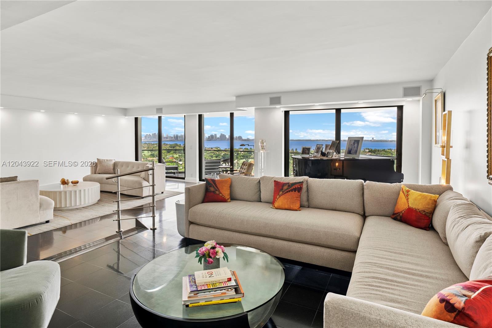A spacious living room features dark tile floors, a large sectional sofa, and floor-to-ceiling windows — 5500 Collins Ave # 1902, Miami Beach FL 33140, MIAMI BEACH, FL