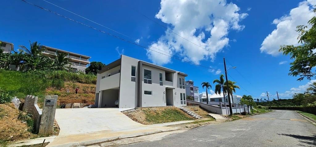 A modern two-story house with a concrete driveway sits on a sloped lot — D-26 MANSIONES PLAYA HUCARES UNIT D-26, NAGUABO, PR
