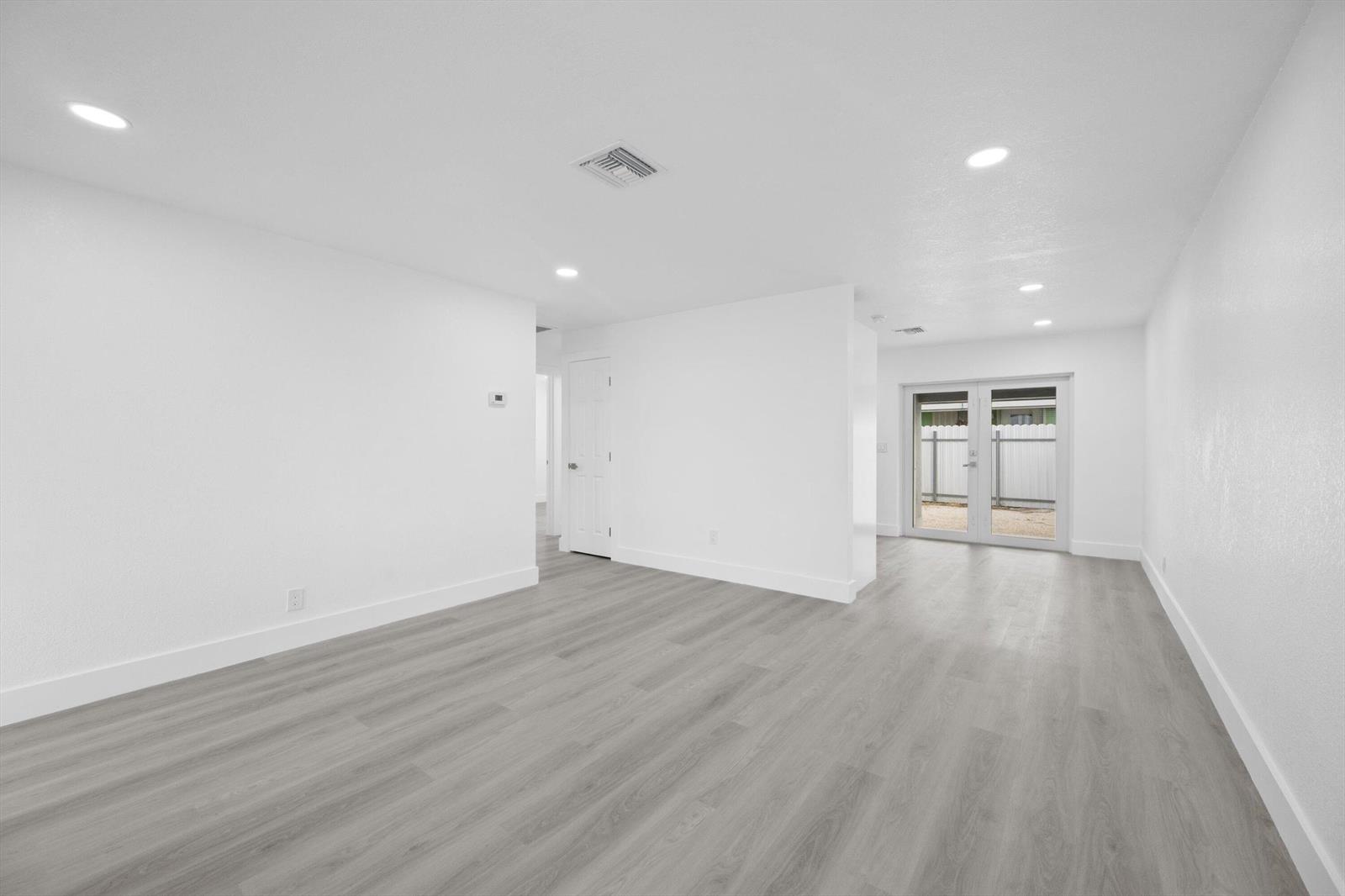 A bright, empty room with white walls, recessed lighting, and light gray wood-look flooring — 2807 Reo Lane # 1, Palm Springs FL 33461, PALM SPRINGS, FL