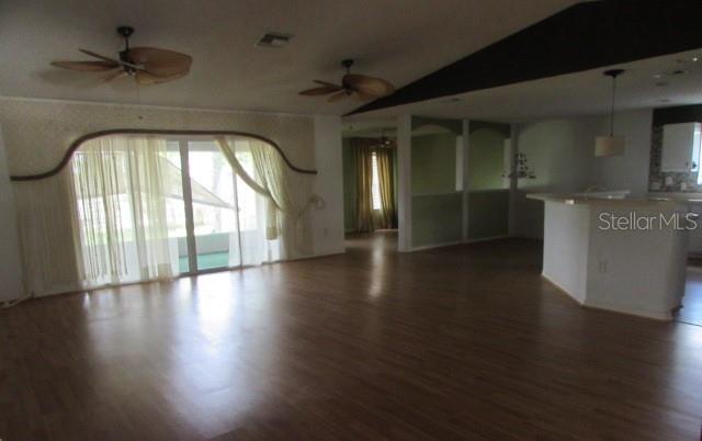 A living room with wood-look flooring, two ceiling fans, and a sliding glass door — 1142 MEADOWBEND DRIVE, LEESBURG, FL