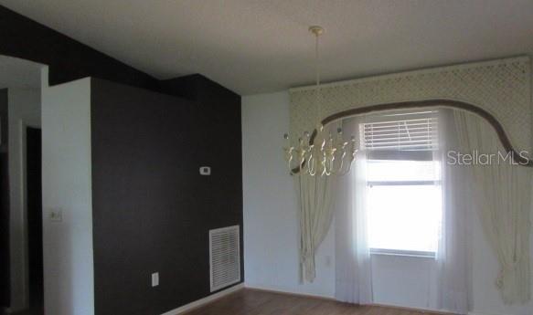 A dining room features a dark accent wall, a chandelier, and a window with curtains — 1142 MEADOWBEND DRIVE, LEESBURG, FL