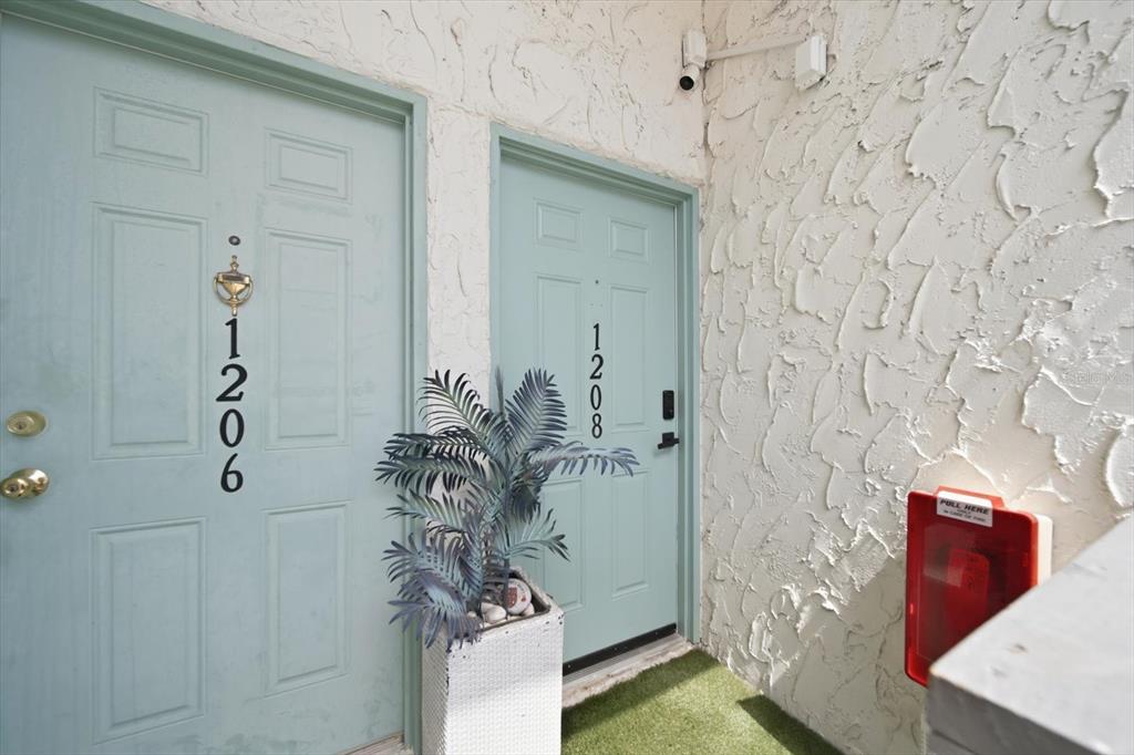 Two light blue apartment doors with house numbers are situated on a textured white wall — 11566 7TH LANE N UNIT 1208, ST PETERSBURG, FL