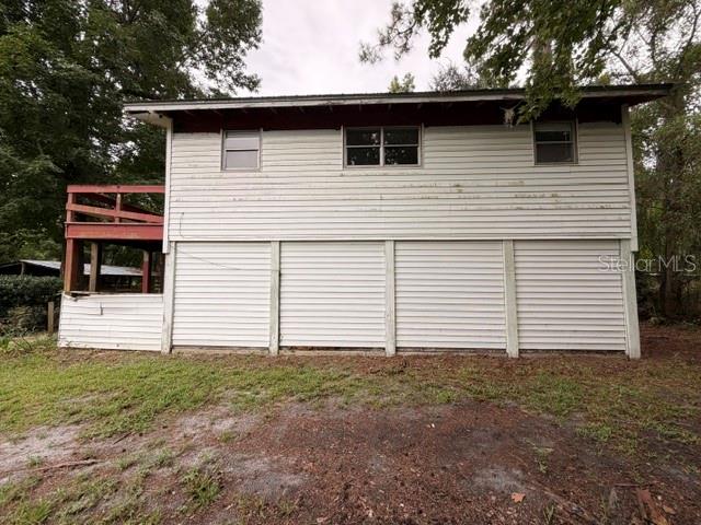 A two-story house with white horizontal siding, a raised lower level, and a wooden deck — 109 HANPARD LANE, PALATKA, FL