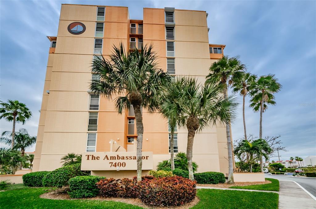 A multi-story tan apartment building with palm trees in front and a prominent entrance sign — 7400 SUN ISLAND DRIVE S UNIT 806, SOUTH PASADENA, FL