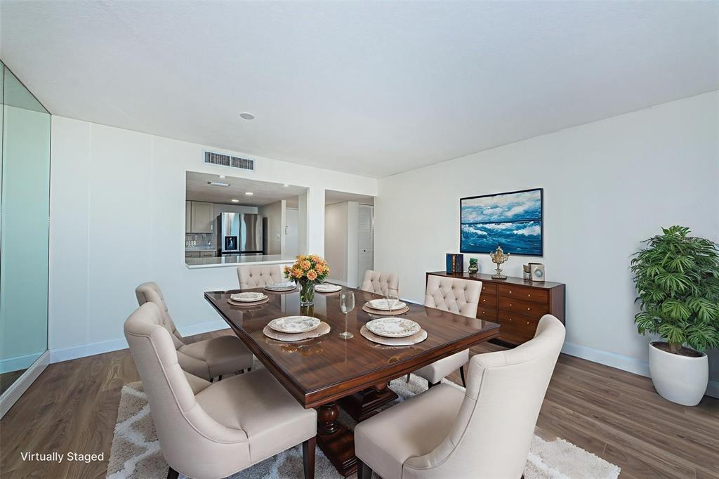 A dining room features a wooden table with upholstered chairs, a sideboard, and a pass-through window — 7400 SUN ISLAND DRIVE S UNIT 806, SOUTH PASADENA, FL