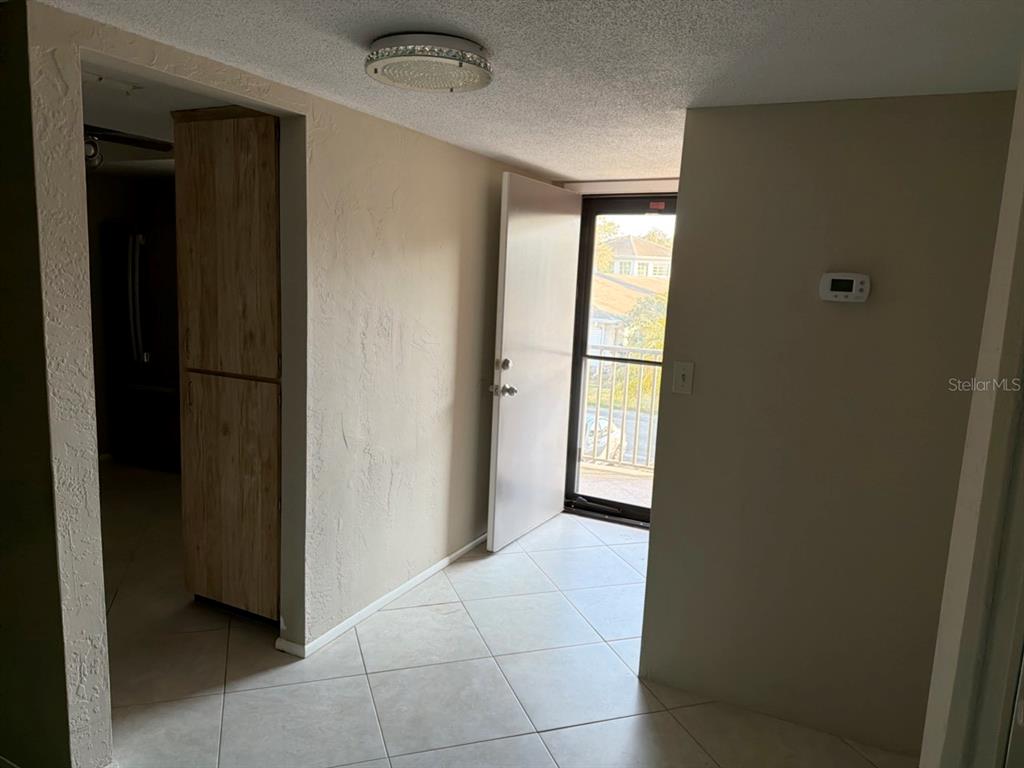 A tiled entryway leads to an open door revealing a balcony with a metal railing — 9815 47TH AVENUE N UNIT 207, ST PETERSBURG, FL