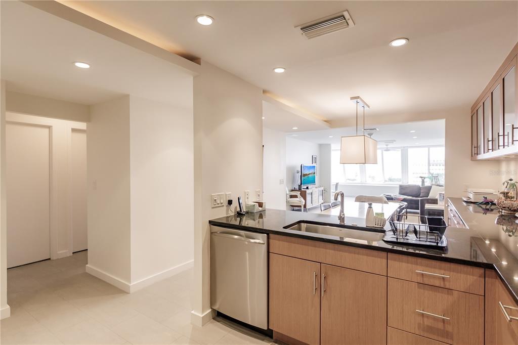 A kitchen with light wood cabinets, black countertops, and a stainless steel dishwasher — 1200 E PEPPERTREE LANE UNIT 402, SARASOTA, FL
