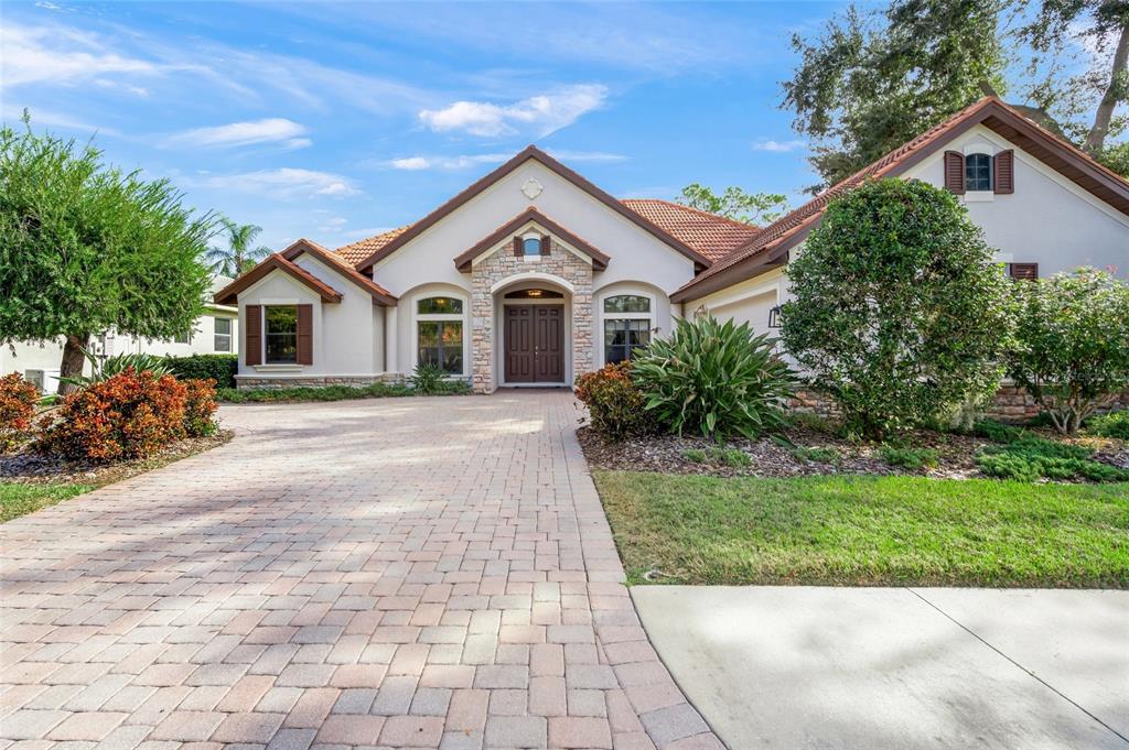 A single-story house with a stone-accented entrance, a paver driveway, and a tiled roof — 5343 NATHANIEL PLACE, SARASOTA, FL