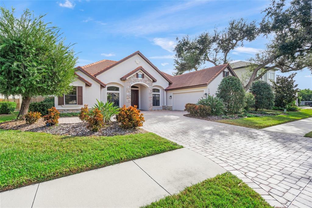 A single-story house with a tiled roof, stone accents, and a paved driveway — 5343 NATHANIEL PLACE, SARASOTA, FL