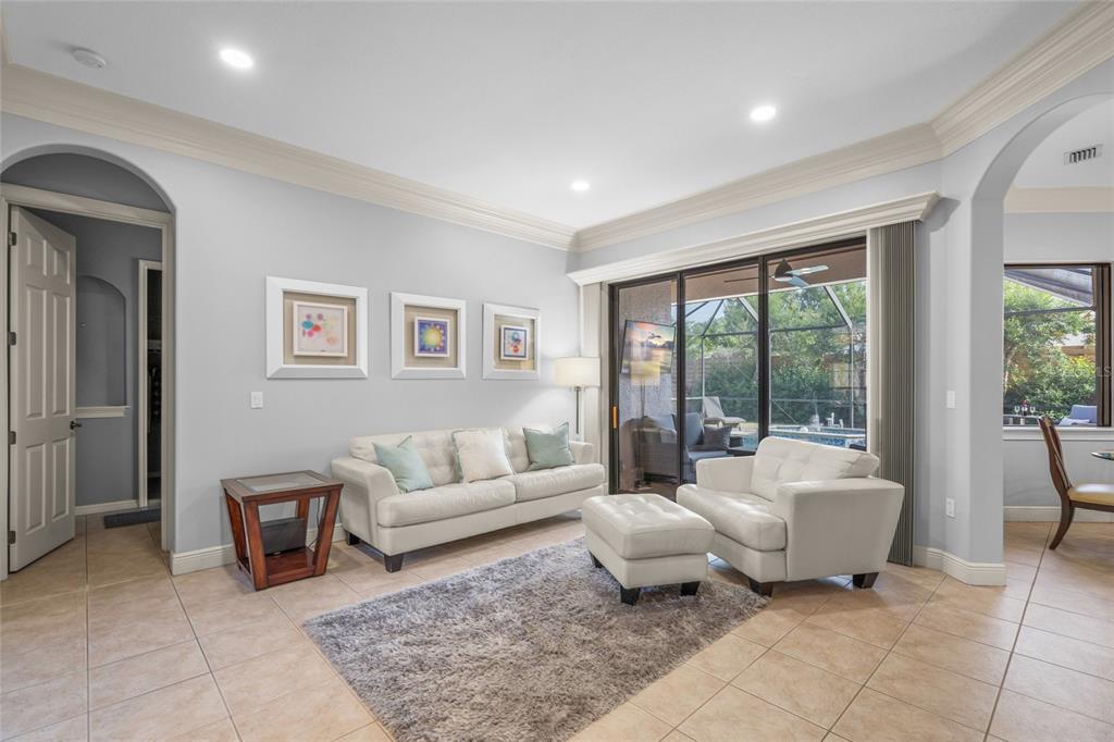 A living room with tile floors, a white sofa, a matching armchair, and sliding glass doors — 5343 NATHANIEL PLACE, SARASOTA, FL