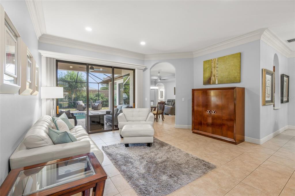 A living room with a white sofa, armchair, area rug, and sliding doors to a patio — 5343 NATHANIEL PLACE, SARASOTA, FL