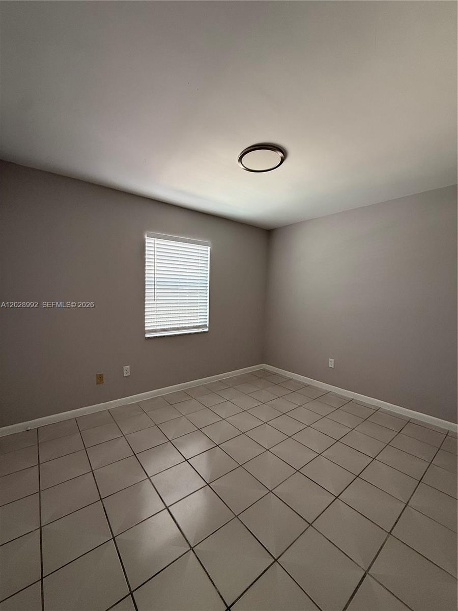 A bedroom features light gray walls, a single window with blinds, and light-colored tile flooring — 6820 W Flagler St # 407, Miami FL 33144, MIAMI, FL