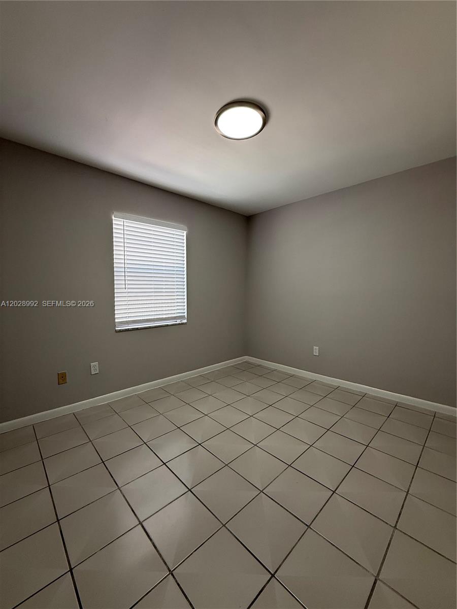 A small, empty room features gray walls, white trim, and light-colored square floor tiles — 6820 W Flagler St # 407, Miami FL 33144, MIAMI, FL