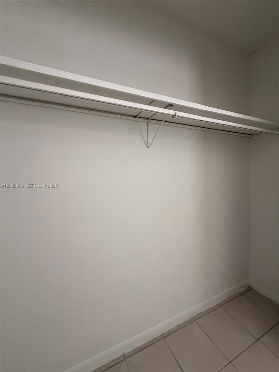 A closet features a white shelf with a metal support bracket and tiled flooring — 6820 W Flagler St # 407, Miami FL 33144, MIAMI, FL