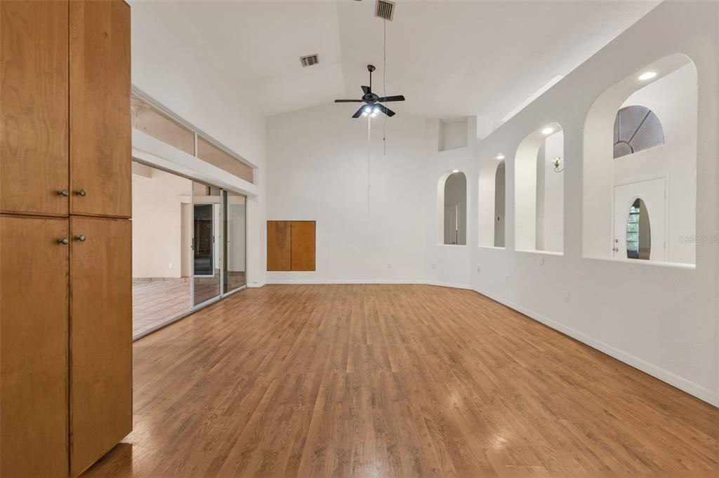 A spacious living room features wood-look flooring, vaulted ceilings, and a series of arched wall niches — 4056 GINGOLD STREET, PORT CHARLOTTE, FL
