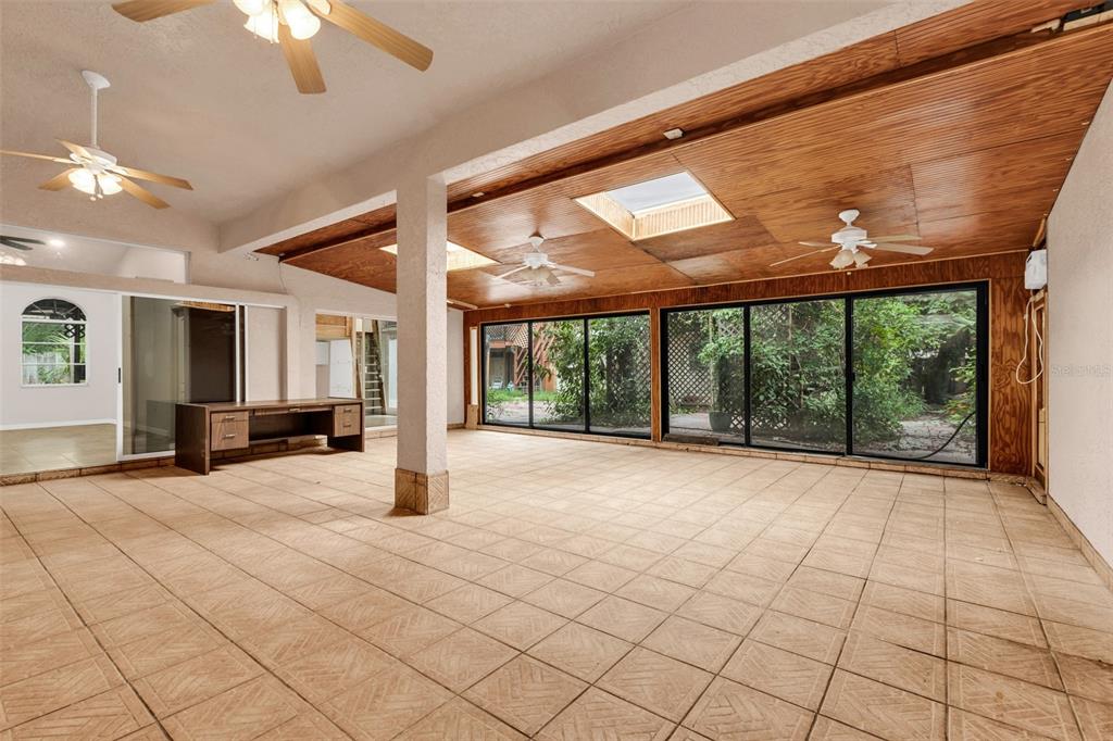A sunroom with tile floors, wood-paneled ceilings, skylights, and sliding glass doors overlooking greenery — 4056 GINGOLD STREET, PORT CHARLOTTE, FL
