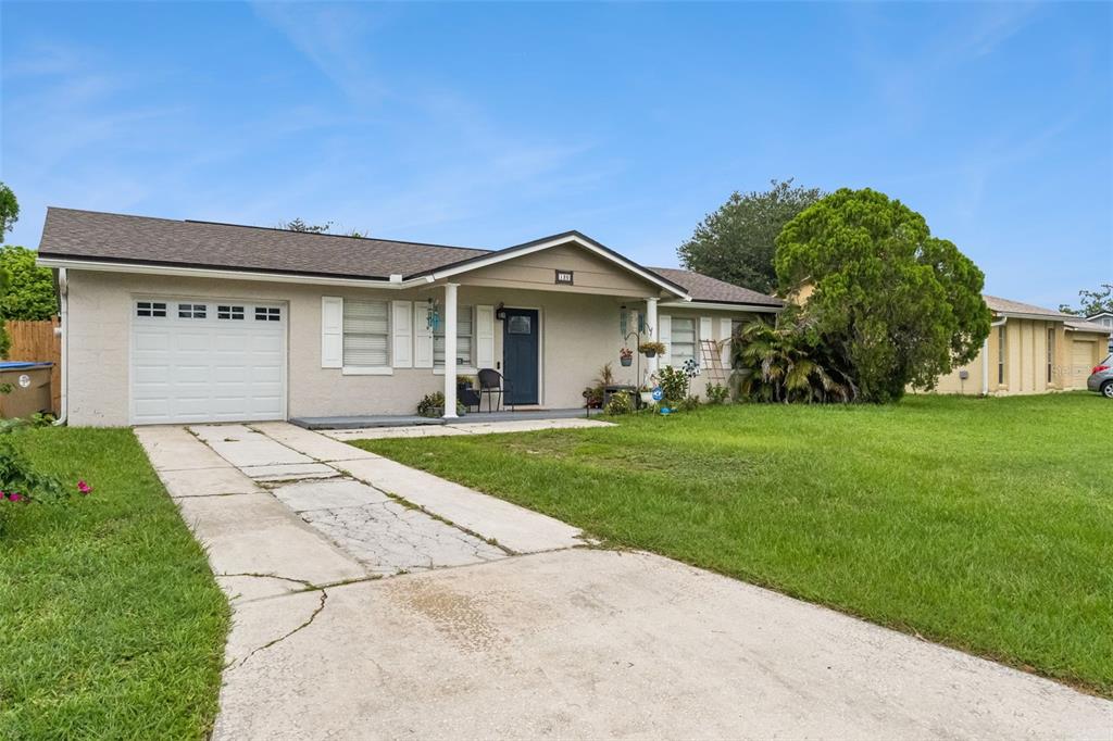 A single-story house with a white garage, a covered porch, and a cracked concrete driveway — 120 MILTA LANE, KISSIMMEE, FL