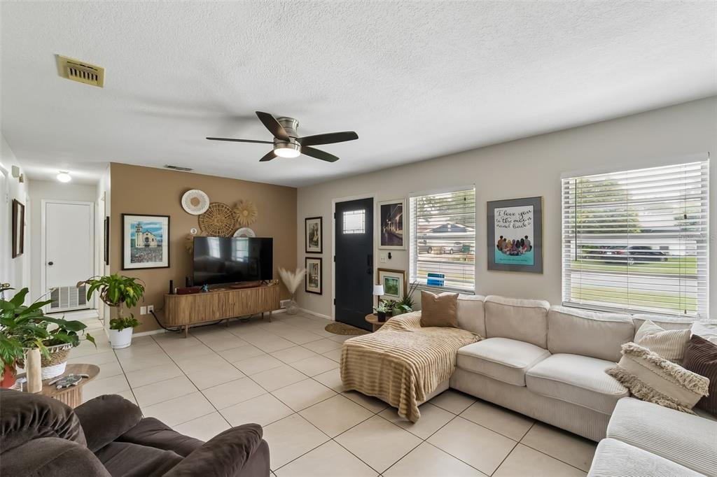 A living room features a beige sectional sofa, a television on a wooden console, and tile flooring — 120 MILTA LANE, KISSIMMEE, FL