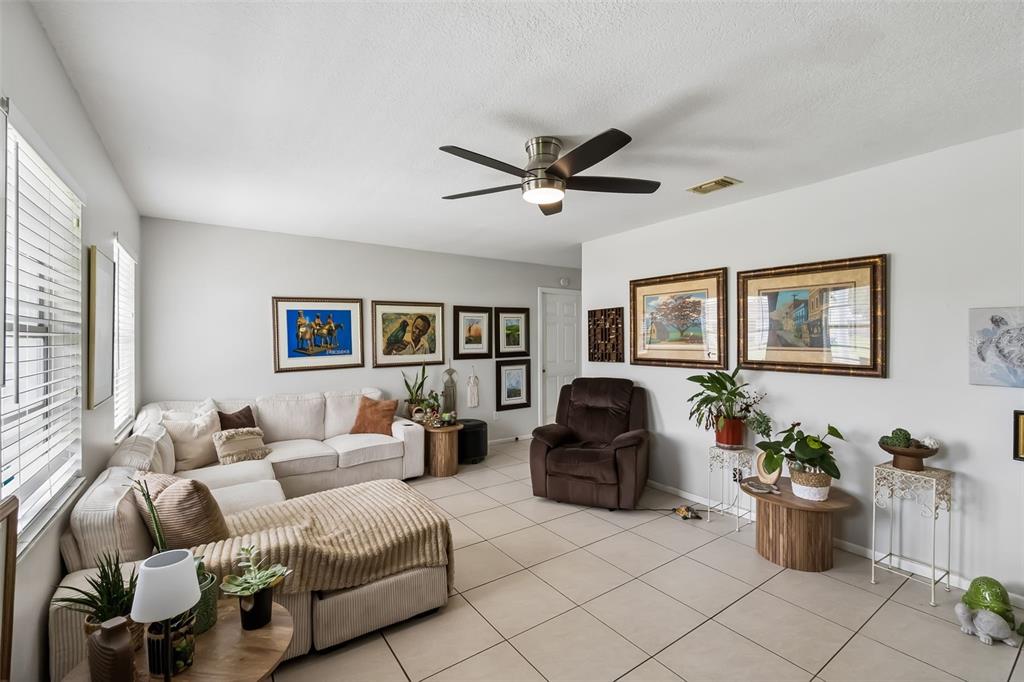 A living room features a beige sectional sofa, a brown recliner, and tiled flooring — 120 MILTA LANE, KISSIMMEE, FL