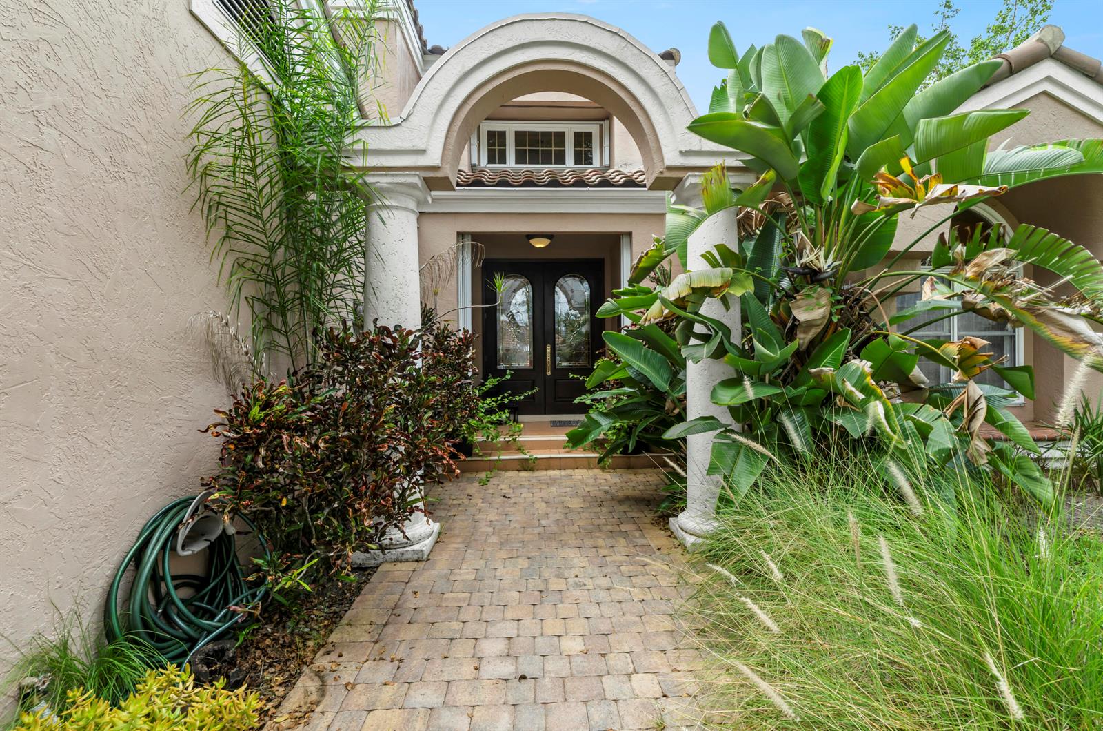 A two-story house with a tiled roof, white garage door, and brick driveway at sunset — 2683 NW 49th Street, Boca Raton FL 33434, BOCA RATON, FL