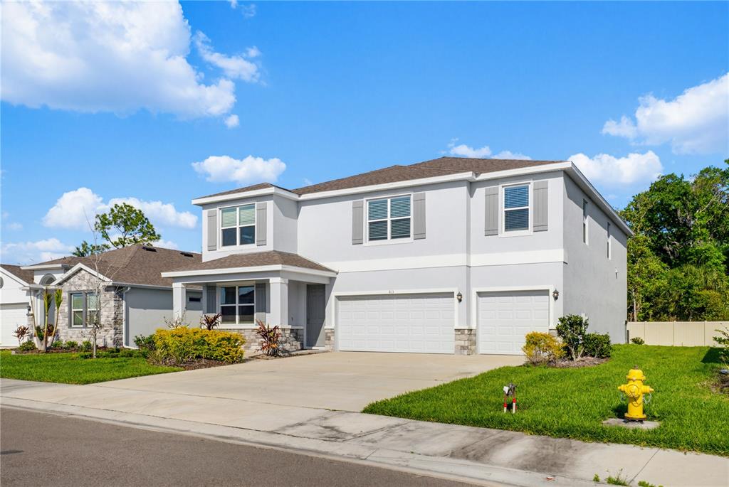 A two-story suburban house with a gray stucco exterior, a three-car garage, and a lawn — 813 161ST STREET E, BRADENTON, FL