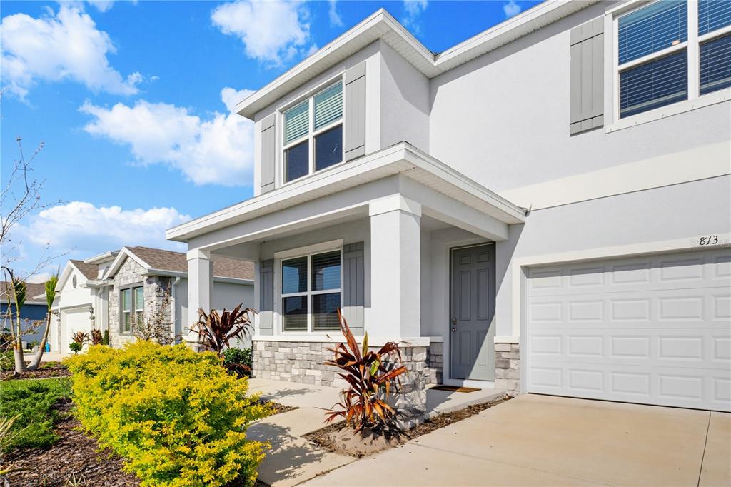 A two-story suburban house features a gray front door, stone accents, and a garage — 813 161ST STREET E, BRADENTON, FL