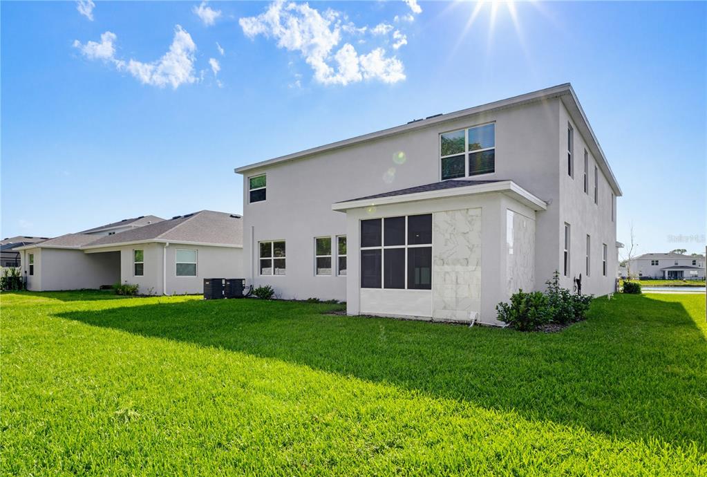 The exterior rear view of a two-story house with a screened-in patio and lawn — 813 161ST STREET E, BRADENTON, FL